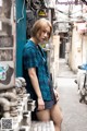 A woman leaning against a wall in an alleyway.