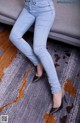 A woman sitting on a couch wearing a pair of jeans.