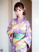 A woman in a purple and green kimono posing for a picture.