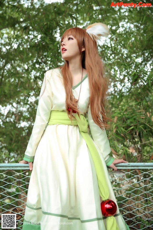 A woman in a white and green dress standing on a railing.