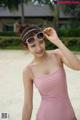 A woman in a pink bathing suit and sunglasses on the beach.