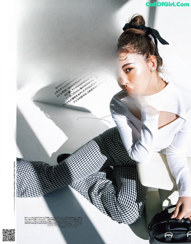 A woman sitting on a white chair with a black bag.