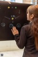 A woman writing on a blackboard with chinese writing on it.