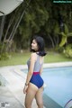 A woman in a blue and red bathing suit standing by a pool.