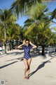 A woman in a polka dot swimsuit standing on a beach.