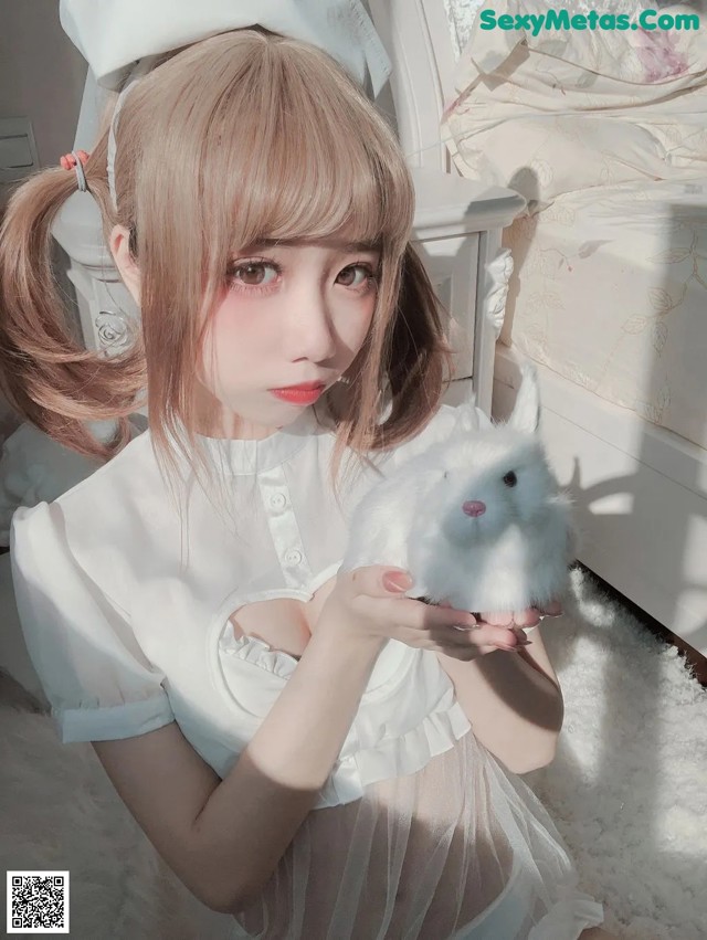 A woman holding a white rabbit in her hands.