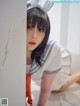 A woman in a sailor outfit leaning against a wall.
