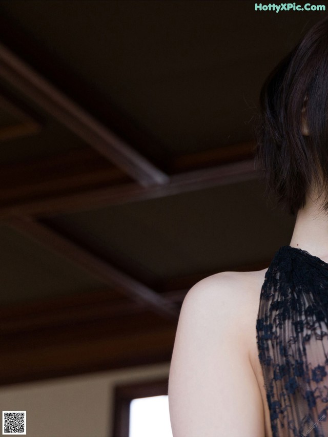 A woman in a black dress standing in front of a window.