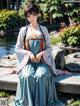 A woman in a blue dress sitting on a stone bench.