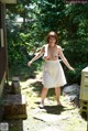 A woman in a white dress is walking in the yard.